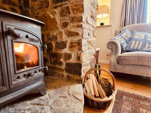 a stone fireplace in a living room with a wood stove at Barn End Cottage in High Bickington