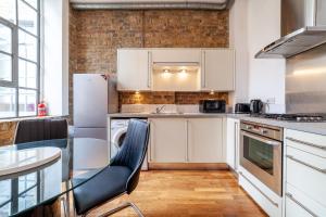 cocina con mesa y nevera blanca en Stunning Loft-Style Duplex 2 BDR Apt in Bow en Londres