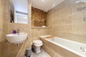 a bathroom with a sink and a toilet and a bath tub at Stunning Loft-Style Duplex 2 BDR Apt in Bow in London