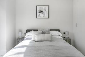 a white bedroom with a bed and a framed picture at New Build-Air Con-2 Bedroom-Two Bathrooms Apt 6 in London