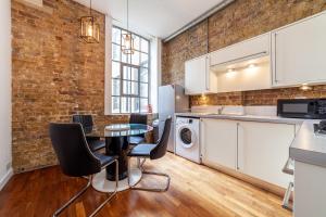 cocina con mesa y pared de ladrillo en Stunning Loft-Style Duplex 2 BDR Apt in Bow en Londres