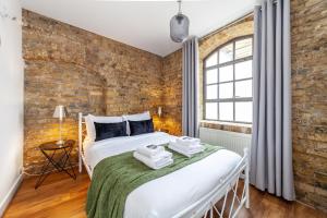 1 dormitorio con cama y pared de ladrillo en Stunning Loft-Style Duplex 2 BDR Apt in Bow en Londres