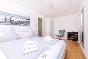 a white bedroom with a large white bed with white pillows at Traumblick in Olpenitz