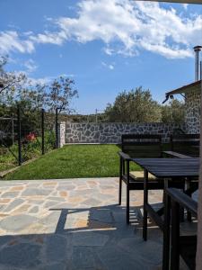 a patio with two benches and a stone wall at Ethos Apartment in Nea Peramos