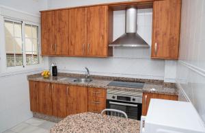 una cocina con armarios de madera y fregadero en Apartamentos Casa Tuli C, ALJARAQUE, en Aljaraque