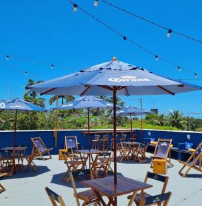 un groupe de tables et de chaises avec parasols dans l'établissement Laika Hostel, à Camburi