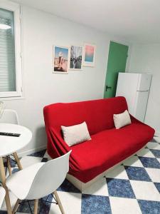 um sofá vermelho num quarto com uma mesa e cadeiras em Porte la chapelle appartement 4 personnes "Appart'5" em Pierrefitte-sur-Seine