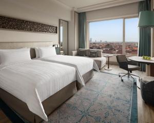 a hotel room with two beds and a large window at Shangri-la Surabaya in Surabaya