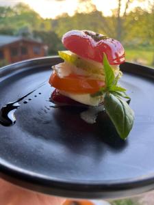 a sandwich on a black plate with a green leaf on it at Les Cocons d AleXan Le studio balnéo aromathérapie 