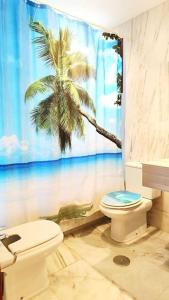 a bathroom with a toilet and a palm tree shower curtain at Villa Valentina in Estepona