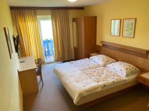a bedroom with a bed and a desk and a window at Pension Carinthia in Unterburg am Klopeiner See