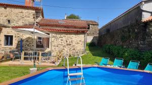 a pool in front of a house with chairs and an umbrella at Casa Fonte do Barro SPA opcional, de pago in Santiago de Compostela