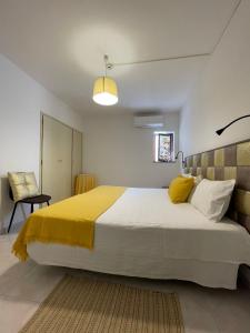 a bedroom with a large bed with a yellow blanket at Só Mar in Vila Nova de Milfontes