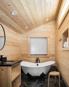 a bath tub in a wooden bathroom with a window at Desolation Hotel Hope Valley in Markleeville