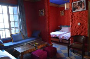 a red room with a bed and a couch and a table at Hotel Sahara in Essaouira