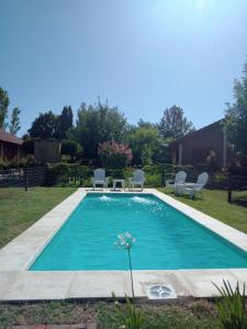 Una piscina en un patio con dos sillas y una mesa. en La Quina., en Villa Rumipal
