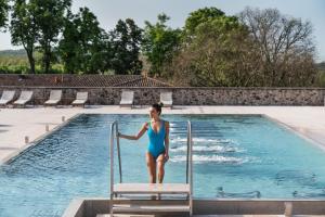 una mujer en traje de baño azul parada en una silla cerca de una piscina en QC Termegarda Spa & Golf Resort, en Calvagese della Riviera