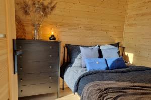 een slaapkamer met een bed met blauwe kussens en een dressoir bij Ale Miejscówka! Całoroczny domek nad jeziorem in Lucień