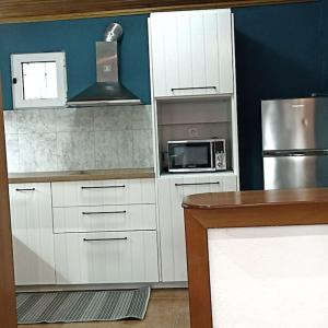 a kitchen with white cabinets and a microwave at ΠΕΤΡΙΝΗ ΚΑΤΟΙΚΙΑ ΣΤΗΝ ΦΥΣΗ in Tagarades