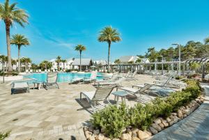 a pool at a resort with chairs and palm trees at Prominence on 30A Pet Friendly Vacation Rentals by Panhandle Getaways in Watersound Beach