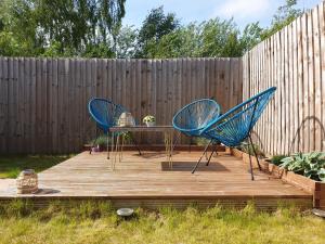 two blue chairs and a table on a wooden deck at Cozy Bedroom with Garden View in Newcastle under Lyme