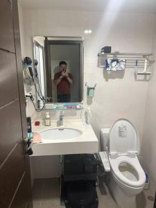 a man taking a picture of a bathroom with a toilet at MingHOW'S House 清水海線溫馨客房有雙人床位、電視、冷氣、獨立衣櫃 in Erh-t'ang-lang