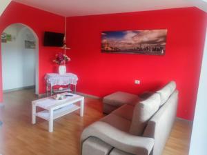 Sala de estar de color rojo con sofá y mesa en Apartamentos turísticos Lemos, en O Pedrouzo