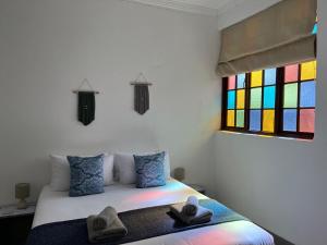 1 dormitorio con 1 cama y una ventana colorida en Forest Gate Estate en Plettenberg Bay