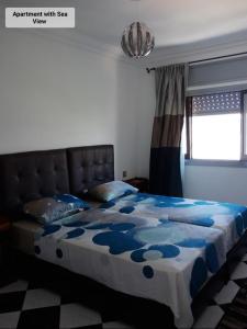 Schlafzimmer mit einem Bett mit einer blauen und weißen Bettdecke in der Unterkunft Martil Center Apartments in Martil