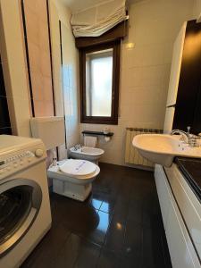 グラードにあるAppartamento Marchesiniのバスルーム(トイレ、洗面台、洗濯機付)