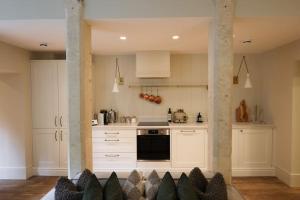 a kitchen with white cabinets and a stove top oven at Brand new Georgian flat in Bath in Bath