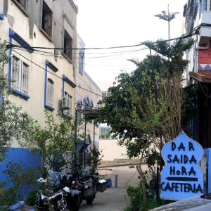 una señal para una tienda con motocicletas estacionadas al lado de un edificio en Dar Saida Hora, en Chefchaouen
