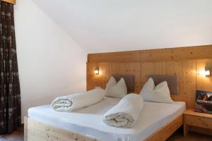 um quarto com uma cama com almofadas brancas em Stiflerhof Apt Alpenrose em Falzes