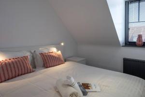 Una cama blanca con un libro y una toalla. en BEACH 52 duplex appartement met terras, en Knokke-Heist