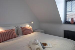 a white bed with a book and a towel on it at BEACH 52 duplex appartement met terras in Knokke-Heist