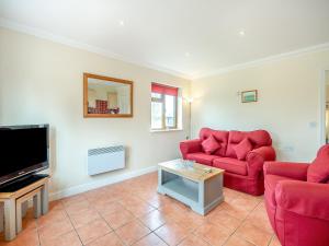 - un salon avec deux canapés rouges et une télévision dans l'établissement Dairy Cottage, à Saint Osyth
