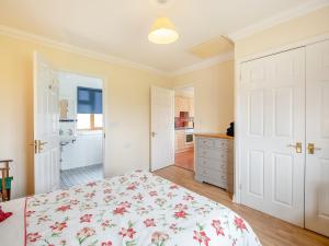 a bedroom with a bed with a floral bedspread at Dairy Cottage in Saint Osyth