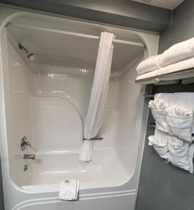 y baño con bañera y toallas blancas. en Comfort Inn - Rehoboth, en Rehoboth Beach