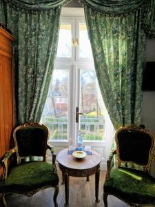 ヘリングスドルフにあるVilla Bleichröderの椅子2脚、テーブル、窓が備わる客室です。