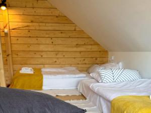 two beds in a attic room with wooden walls at Scandinavian house overlooking the lake in Klepnica