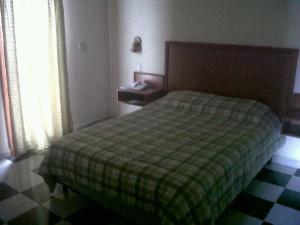 1 dormitorio con 1 cama con manta verde a cuadros en Apart-Hotel River View, en Tegucigalpa