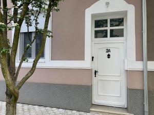een witte deur aan de zijkant van een roze huis bij Apartman Golden in Senta