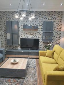 een woonkamer met een gele bank en een tv bij Apartman Golden in Senta