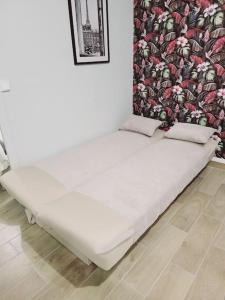 - un lit blanc dans une chambre avec un mur dans l'établissement Family flat Stade de France airport CDG Le Bourget "Appart'7", à Pierrefitte-sur-Seine