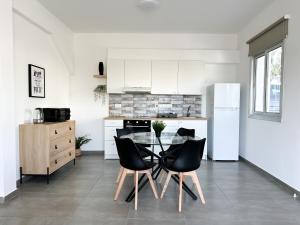 eine Küche mit einem Glastisch und schwarzen Stühlen in der Unterkunft Vacation mode Apartment in Ayia Napa