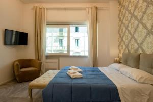 Un dormitorio con una cama azul con una silla y una ventana en Relais Vittorio Veneto - Luxotel & Apartotel, en Salerno