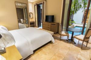 a bedroom with a bed and a television and a table at Bastión Luxury Hotel in Cartagena de Indias