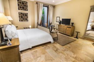 Dormitorio con cama, escritorio y TV en Bastión Luxury Hotel, en Cartagena de Indias