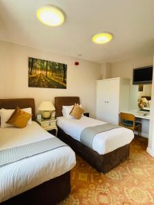 a hotel room with two beds and a desk at Fairlight Guesthouse in Glenridding