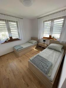 two beds in a bedroom with two windows at Apartament Rybical in Ryn